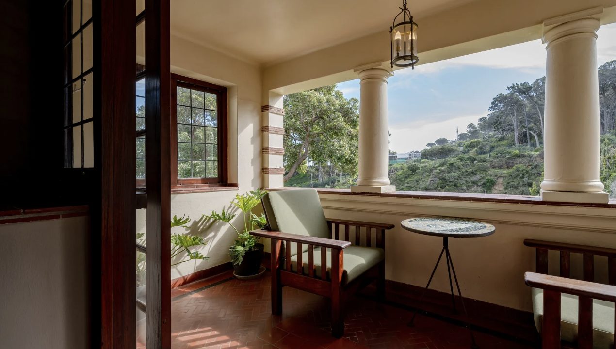 A shaded veranda with a Morris chair, looking to the hillside